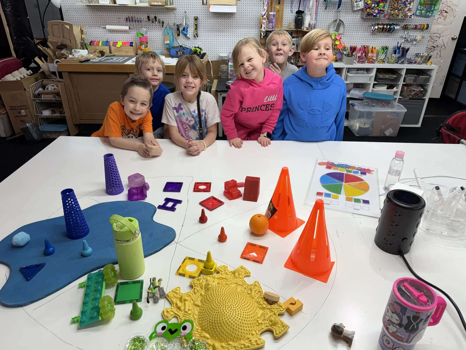 A group of young artists behind a studio table filled with colorful shapes