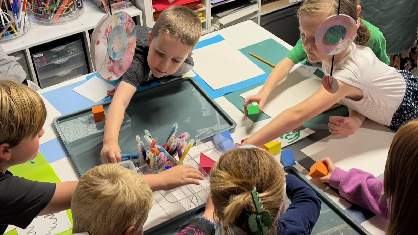 Young artists exploring materials together around an art table