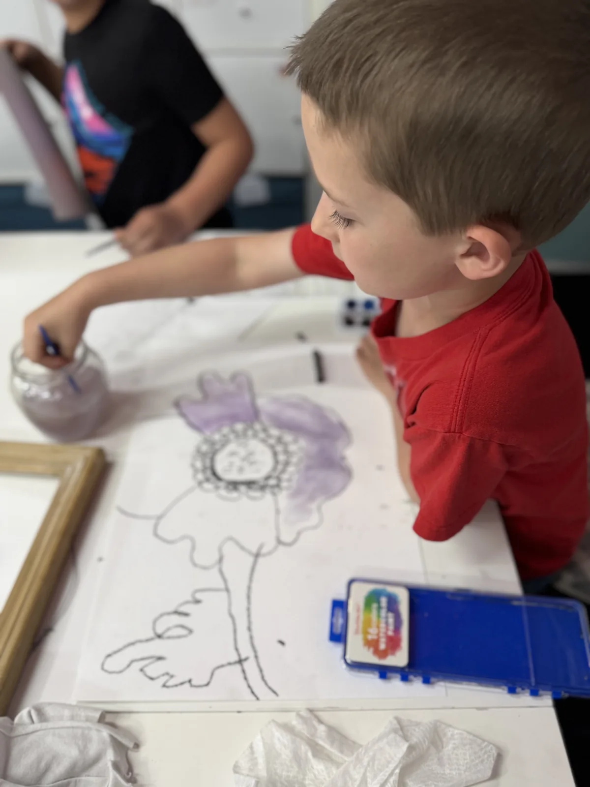 An artist drawing at a studio table beside an observation reference