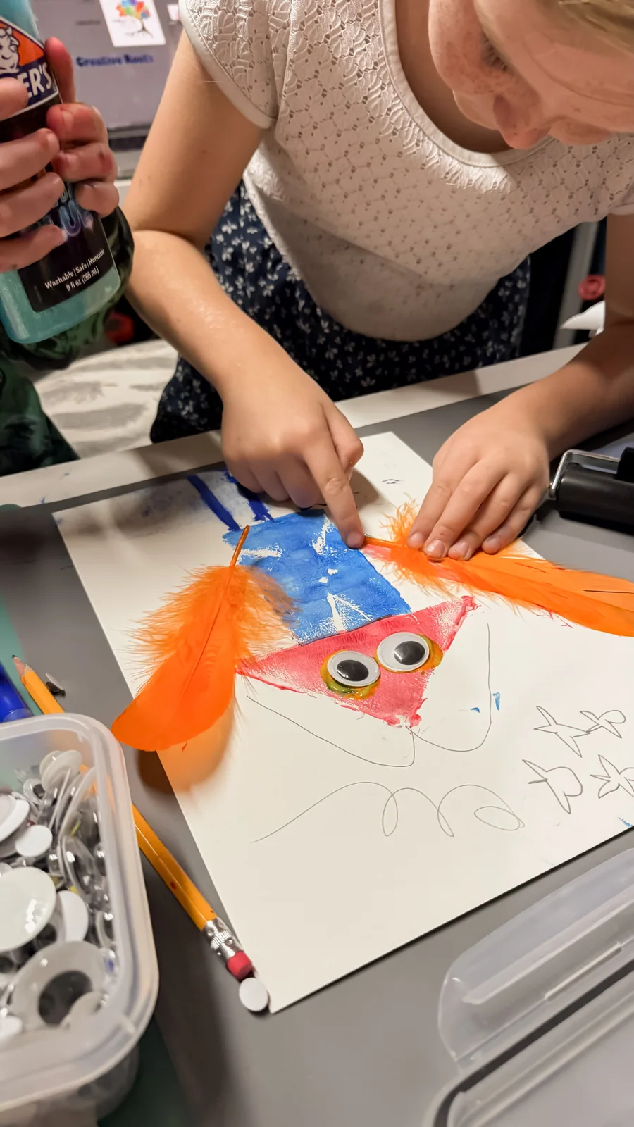 An artist arranging bright paper pieces into a fish collage