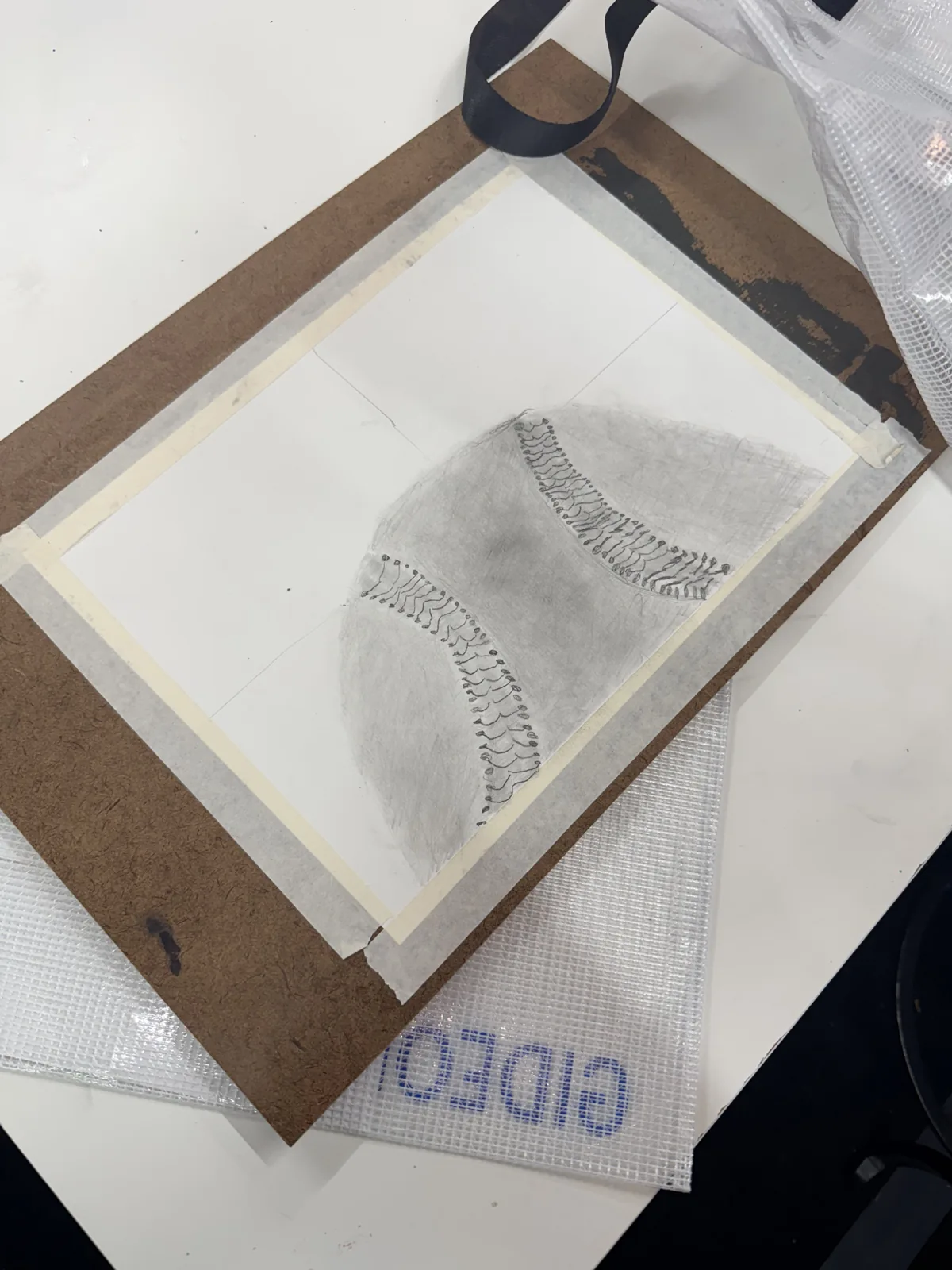 A graphite drawing on a board beside a geometric reference object