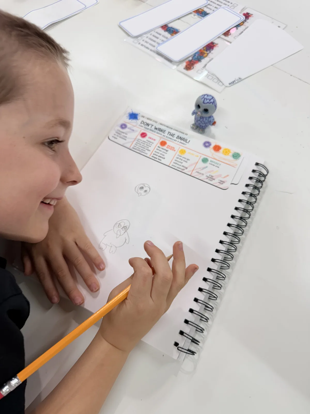 A young artist smiling while exploring a drawing journal