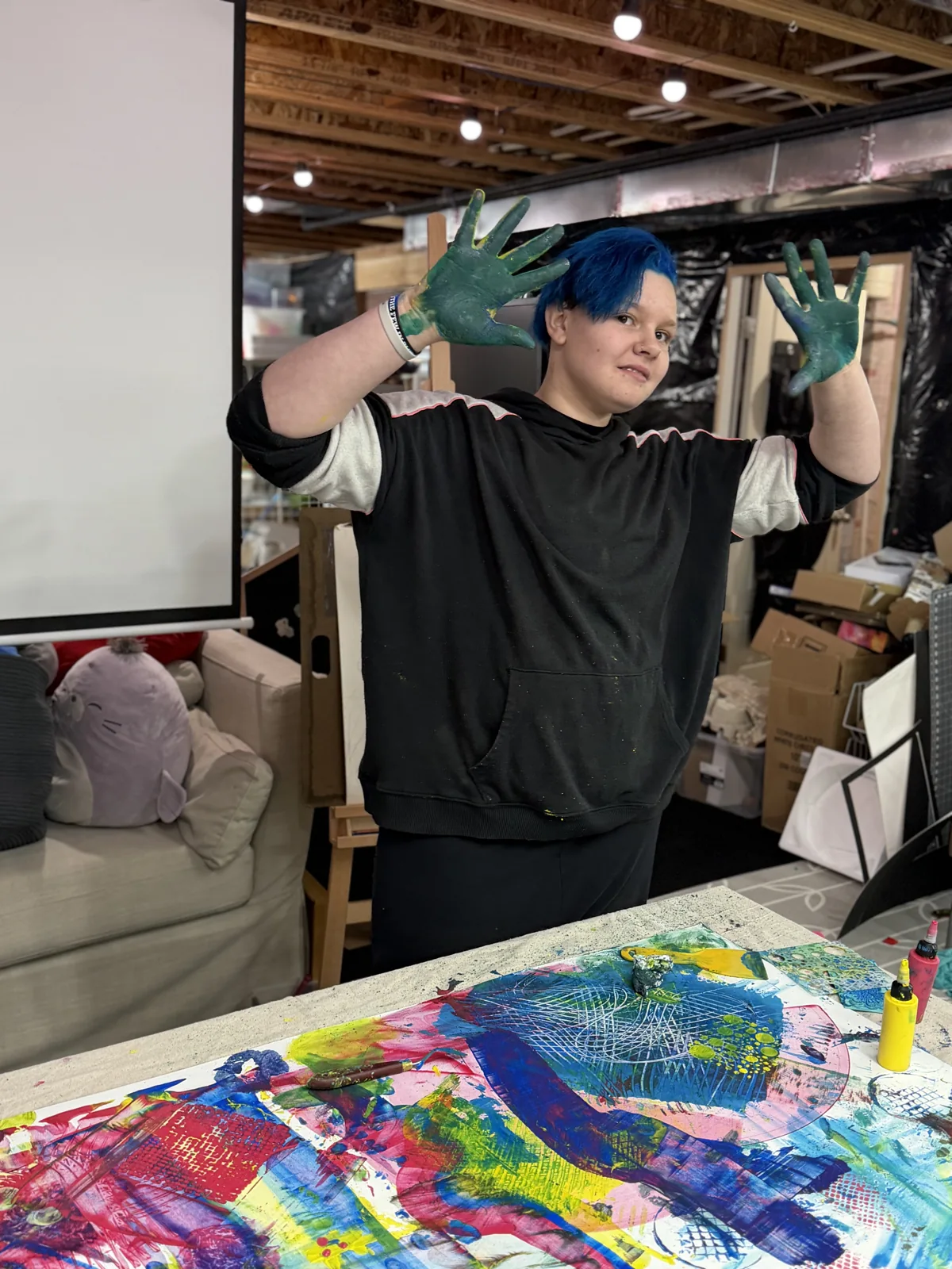 An artist beside a colorful shared studio painting
