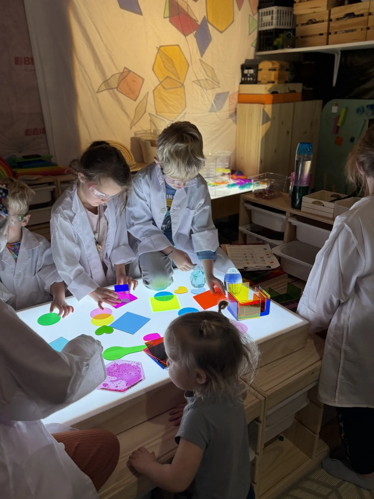 Young artists exploring bright colors and shapes together at a light table