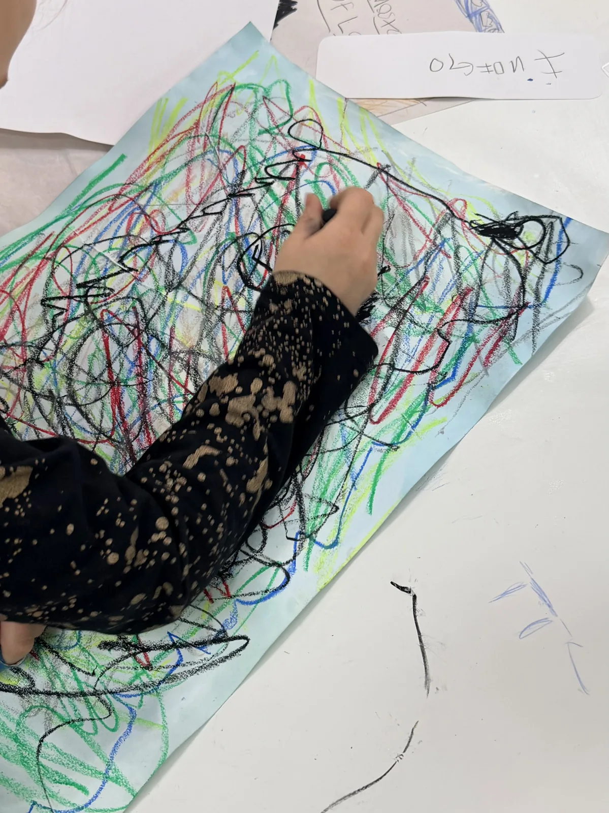 A young artist layering energetic colored lines on a large drawing
