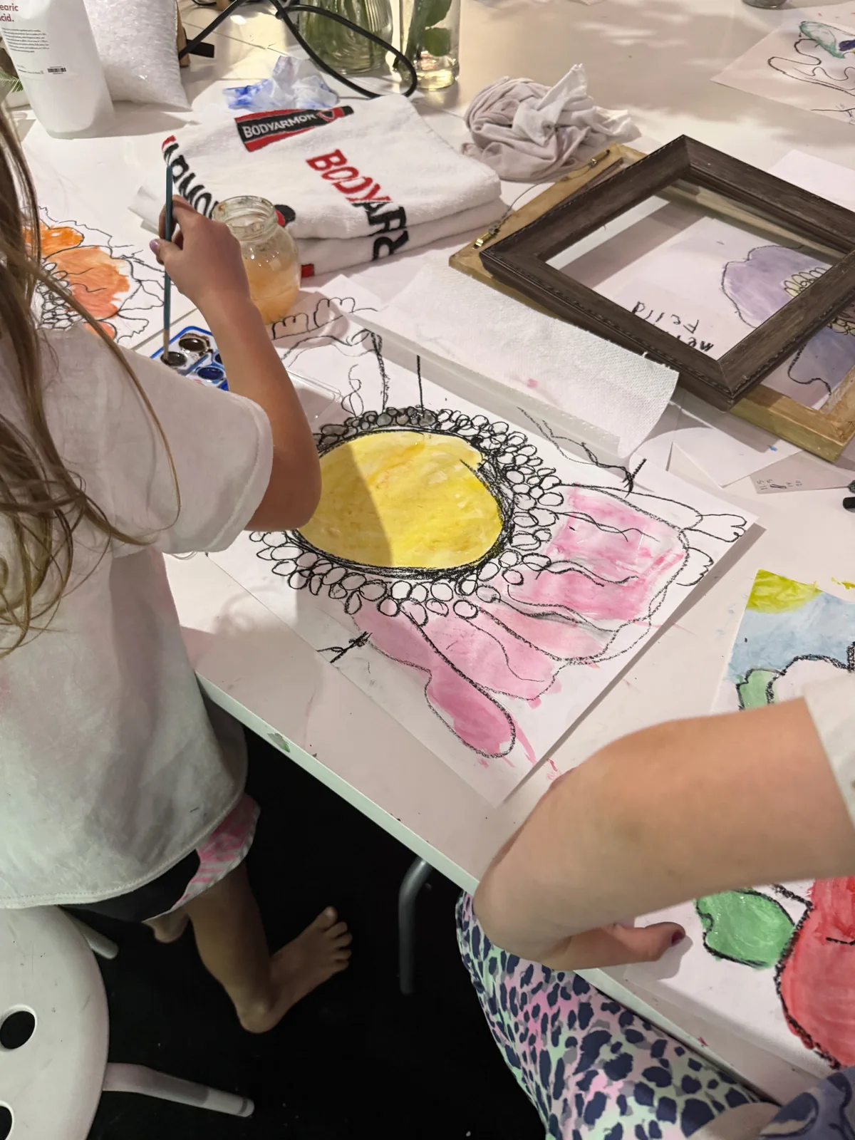 Young artists combining paint and drawing on large sheets of paper