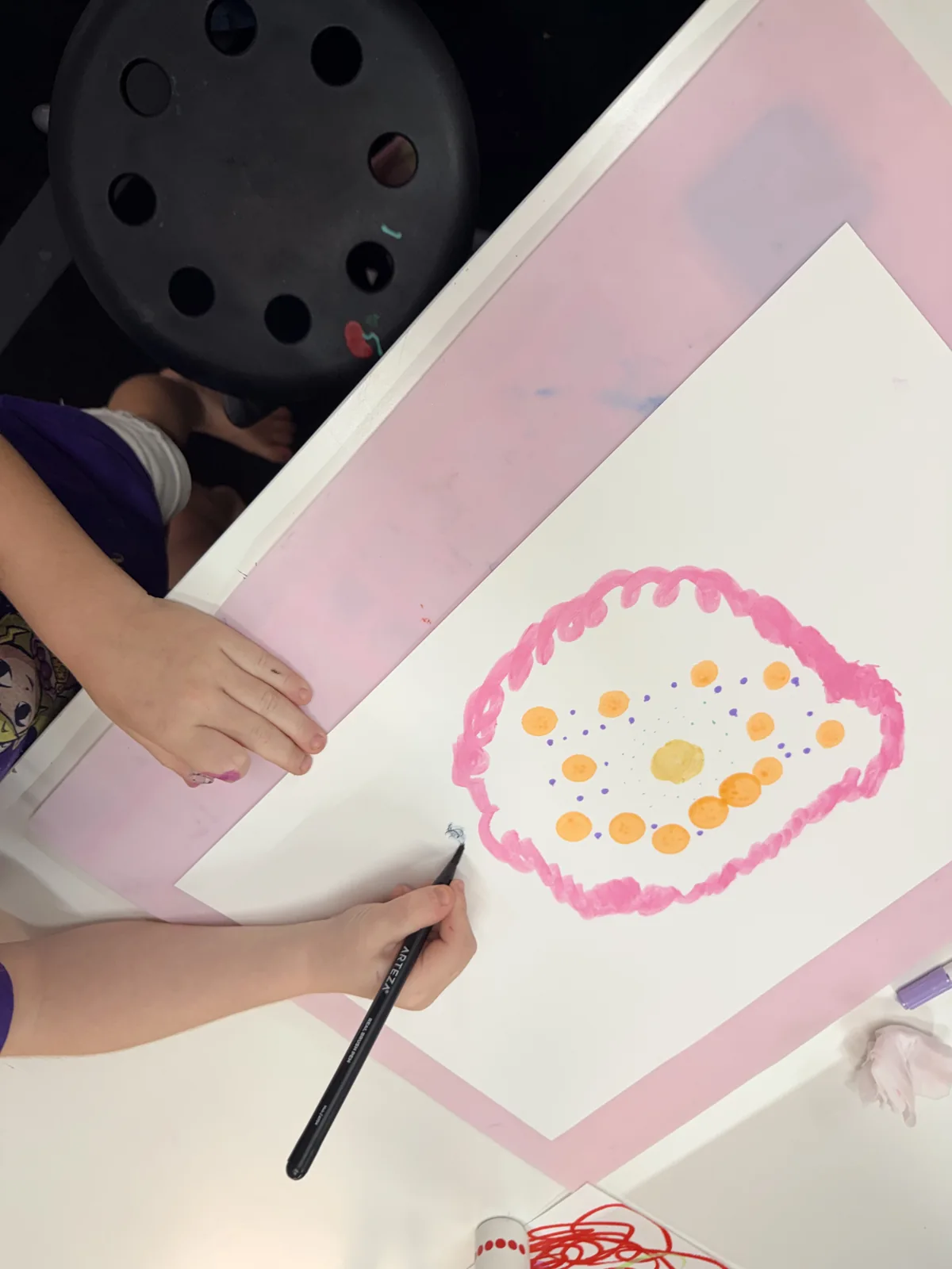 An artist painting a colorful circular pattern on paper