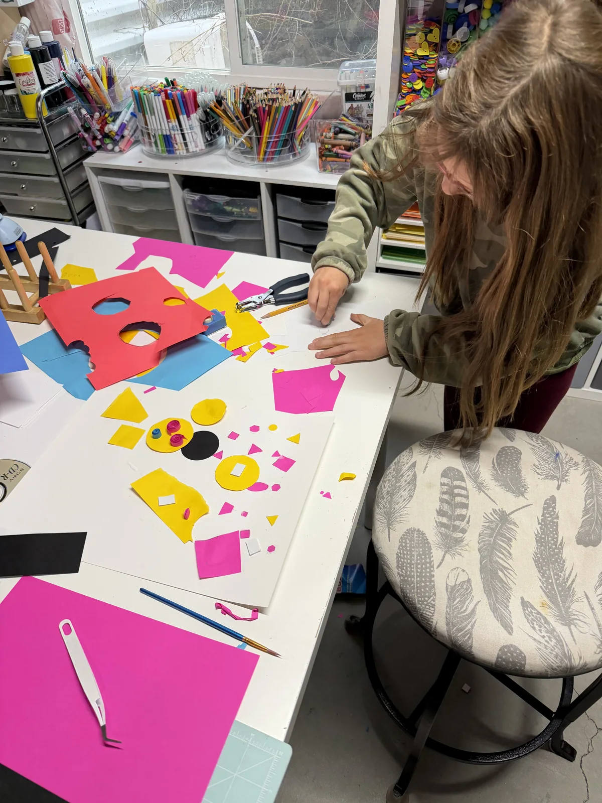 An artist arranging bright geometric paper shapes into a composition