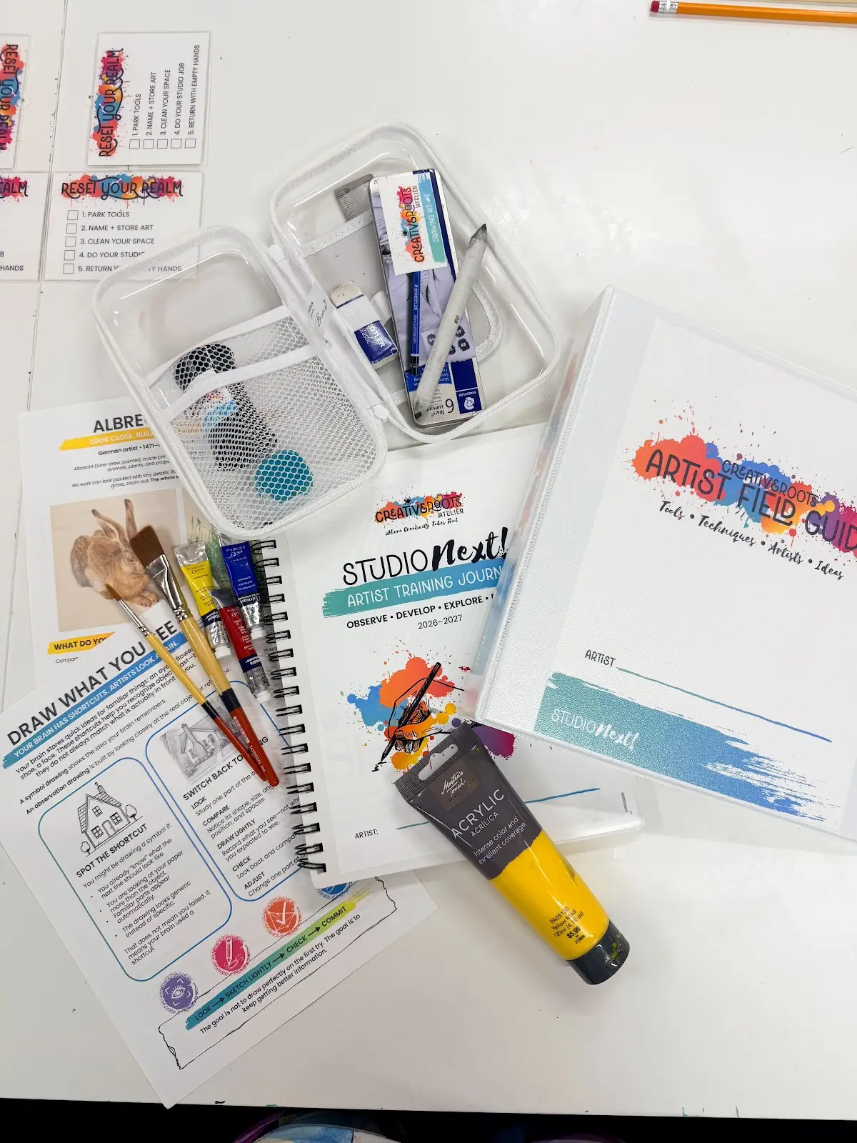 Sketchbooks, drawing references and colorful art tools arranged on a studio table